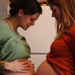 Two pregnant women comparing their very large bellies