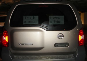 Nissan Xterra SUV with a sign in the window saying "This is a rental; I own a Prius".